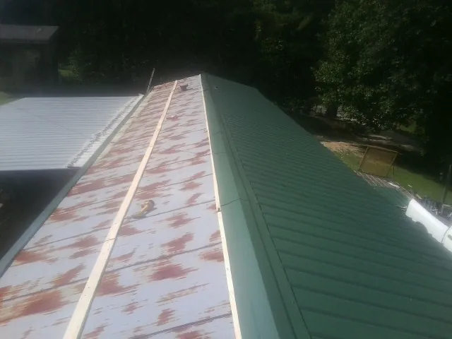 Old rusted panels beside newly installed green metal roofing — Wind Damage Roof Repair by Roofing Brothers in Mount Kisco