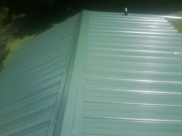 New green metal panels meeting at the ridge of a roof — Flat Roof Repair work by our crew in Mount Kisco