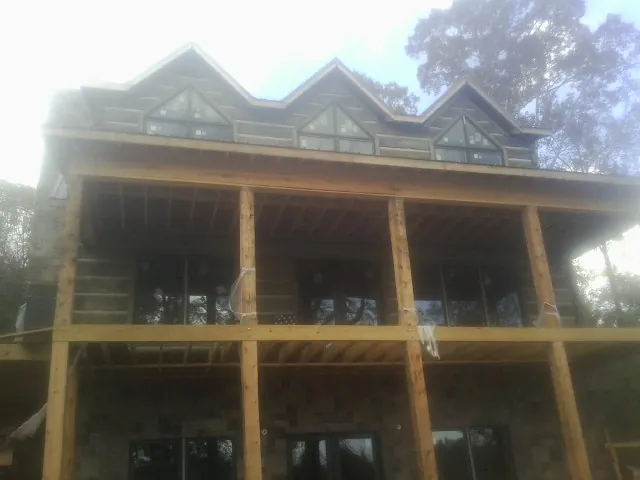 Dormers and porch framing on a large log home under construction — Roof Coating work by our crew in Mount Kisco