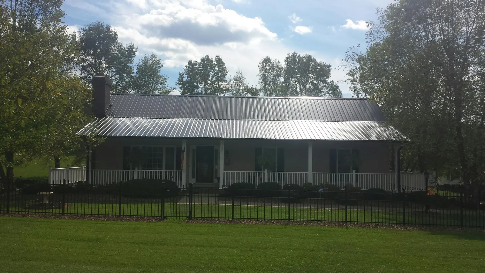 Gray metal roof on a brick ranch with a full width front porch — Gutter Guard Installation work by our crew in Mount Kisco