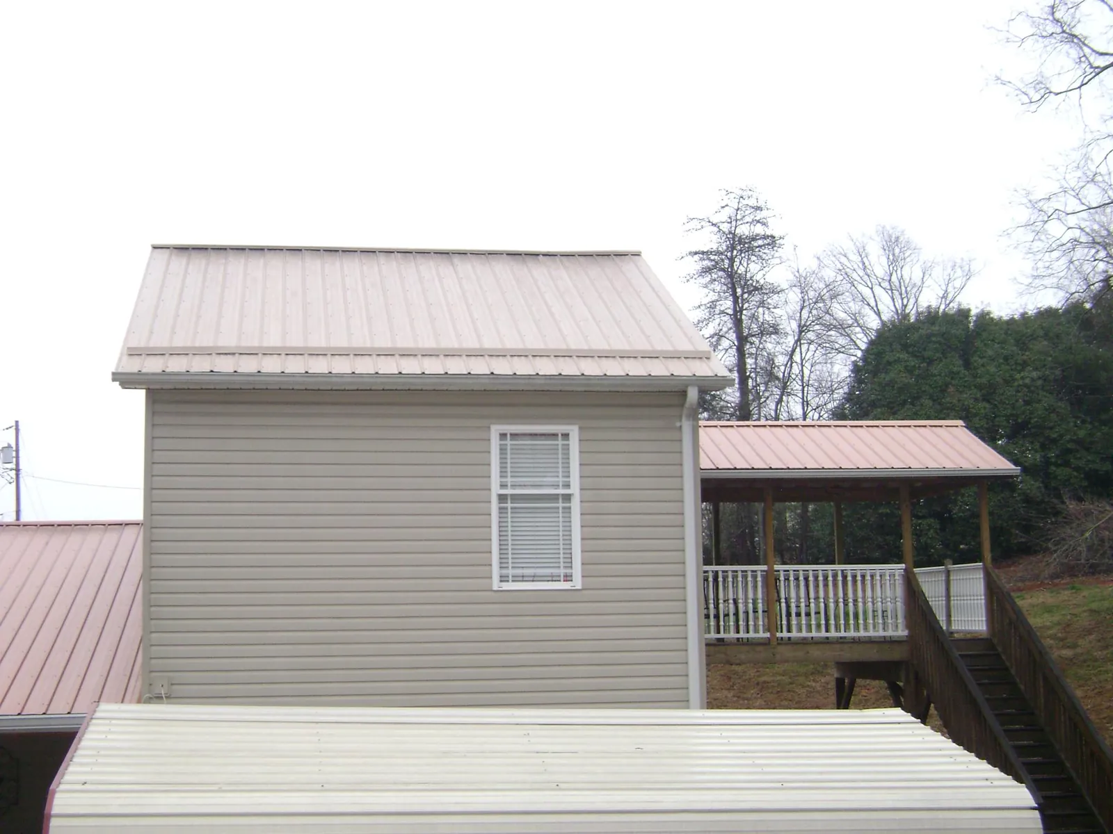 Tan metal roofs on a two story addition and attached porch, from a Roof Replacement job in Mount Kisco