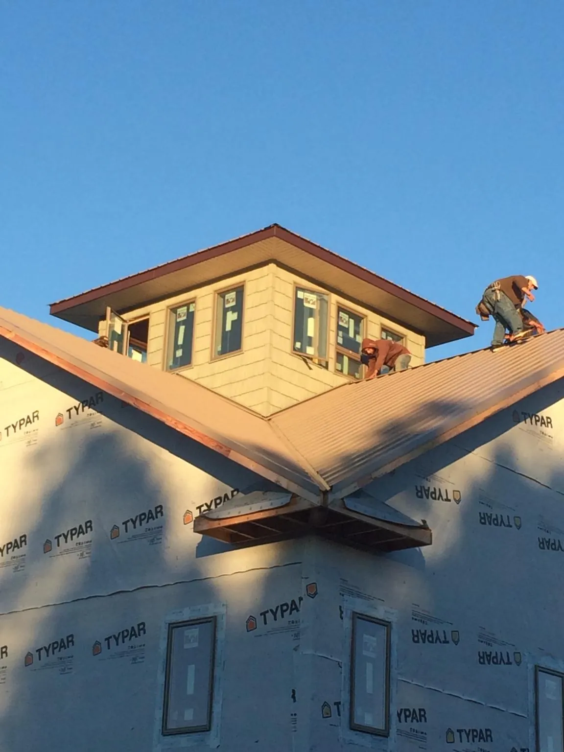 Roofers working around a rooftop cupola on a new metal roof at sunset — Roof Waterproofing in Mount Kisco by Roofing Brothers